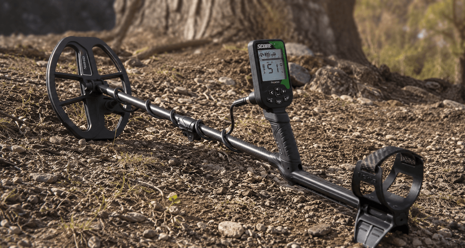 Caja de control del Detector de metales Nokta Score encendido sobre suelo pedregoso de montaña.