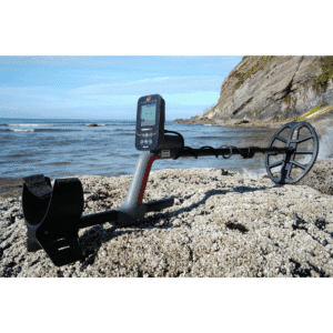 Primer plano de la pantalla LCD del detector Minelab Vanquish 560 Standard mostrando un índice de discriminación numérico negativo sobre un fondo de piedras de río.