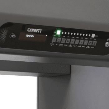 Consola de comandos del detector de metales de paso Garrett Paragon con indicadores de alarma, volumen y botones de menú para personal de seguridad.