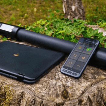 Smartphone rugerizado con la interfaz de control de OKM y elementos de hardware del escáner Fusion Light en la naturaleza.