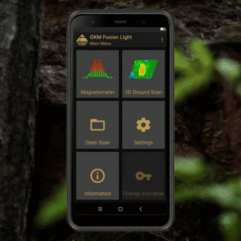 Captura de pantalla de la aplicación OKM Fusion Light en un smartphone rugerizado mostrando el menú principal con iconos para Magnetómetro y Escaneo de Suelo 3D sobre fondo de bosque borroso.