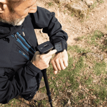 Operador en entorno natural utilizando el escáner de suelo OKM Rover UC y visualizando datos en el smartwatch de control en su muñeca.